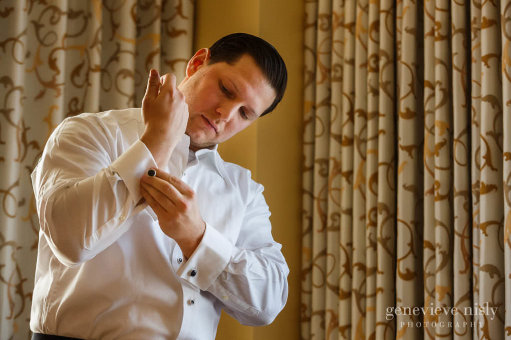 Groom fastens cufflink while preparing for his wedding at the Ritz Carlton in Cleveland.