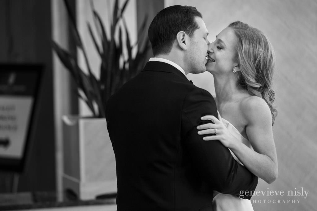 Bride and groom kissing with a smile on her face.
