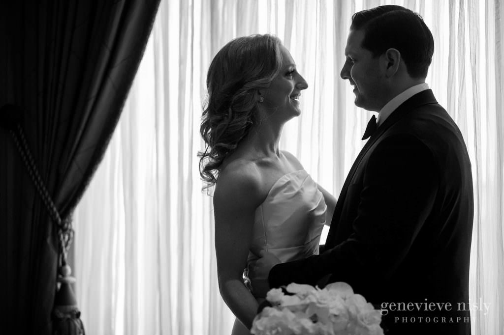 Black and white portrait of bride and groom in front of a window.
