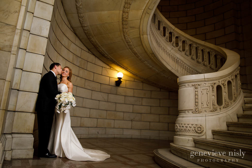 Groom kisses bride's cheek near the staircase at the old courthouse.