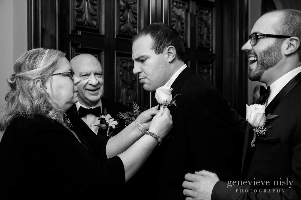 Mom helps son pin a flower on his jacket at the wedding ceremony.