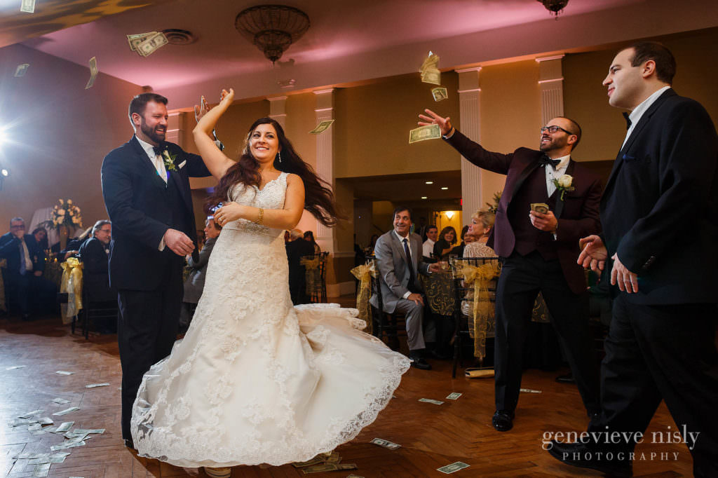 Brother tosses dollar bills on wedding couple during their first dance at the reception.