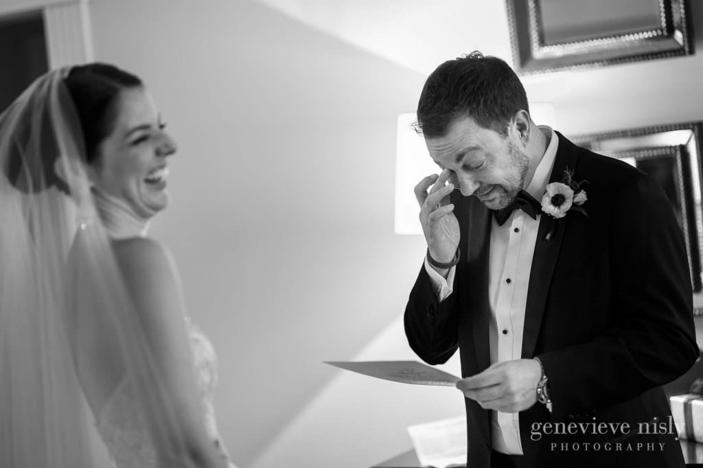 The bride laughs while the groom wipes a tear as they read letters to each other.