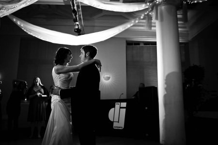 A black and white photo of a bride and groom backlit while slowing dance on the ballroom floor near a pillar at the Massimo da Milano under ceiling draping light with twinkle lights.