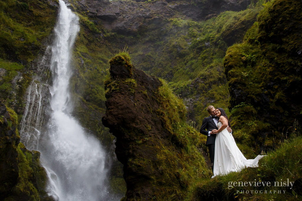 Bride and groom standing near a waterfall during their destination wedding in Iceland.