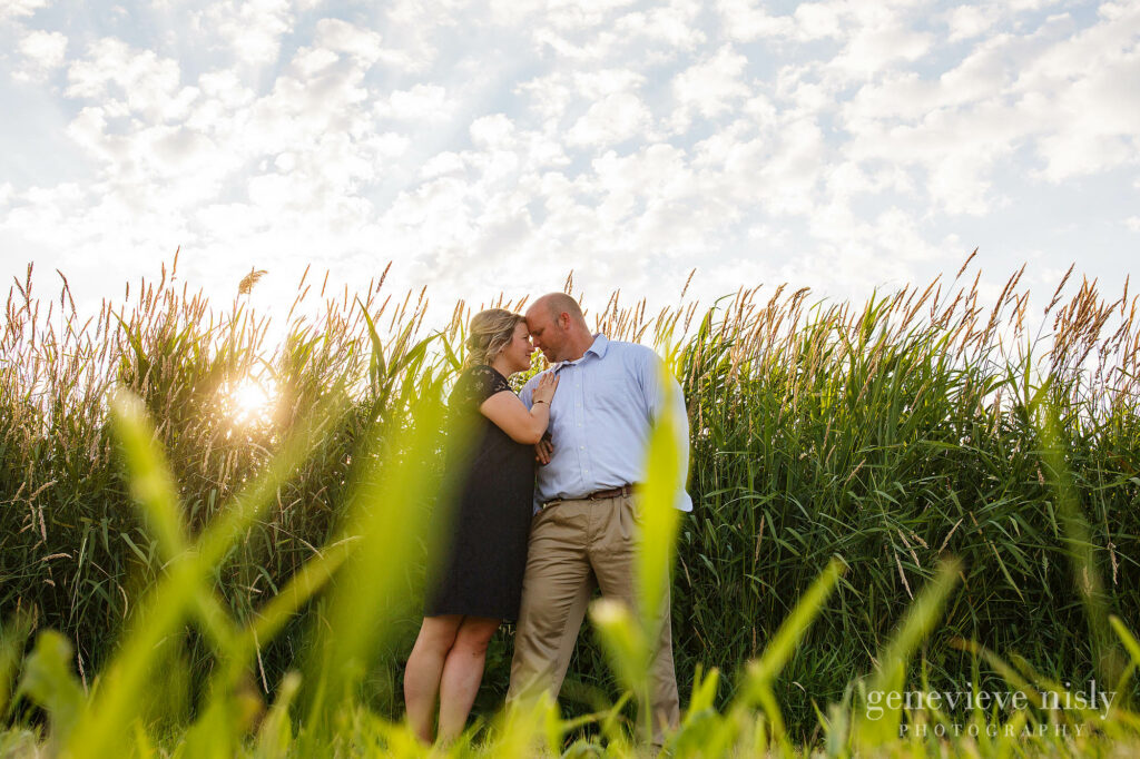 A huron engagement session with couple standing in front of tall grasses near the break wall.