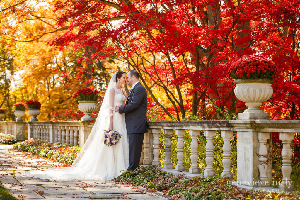 Akron wedding couple at Stan Hywet Hall and Gardens in front of red and yellow fall colors.