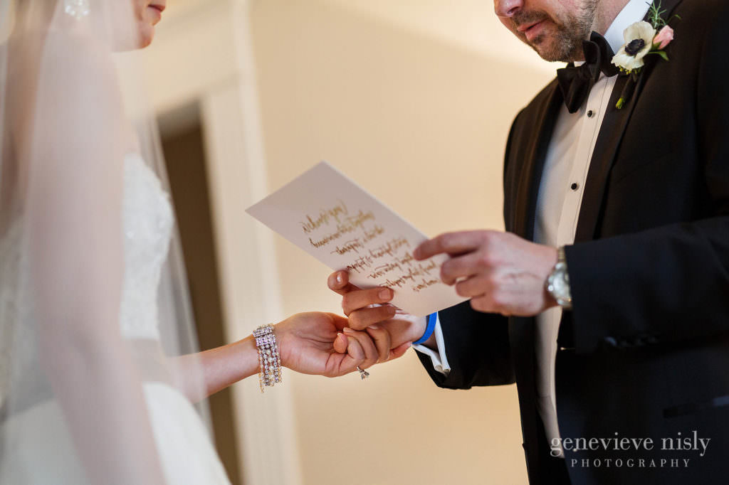 The bride holds the groom's hand as he reads the letter she wrote for him.
