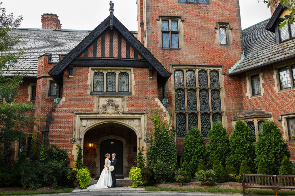 A bride and groom on their wedding day in front of the manor house at Stan Hywet Hall and Gardens in Akron, Ohio.