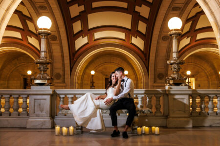 Elegant couple sharing an intimate moment in a grand, ornate old courthouse, illuminated by the ambient glow of candles.